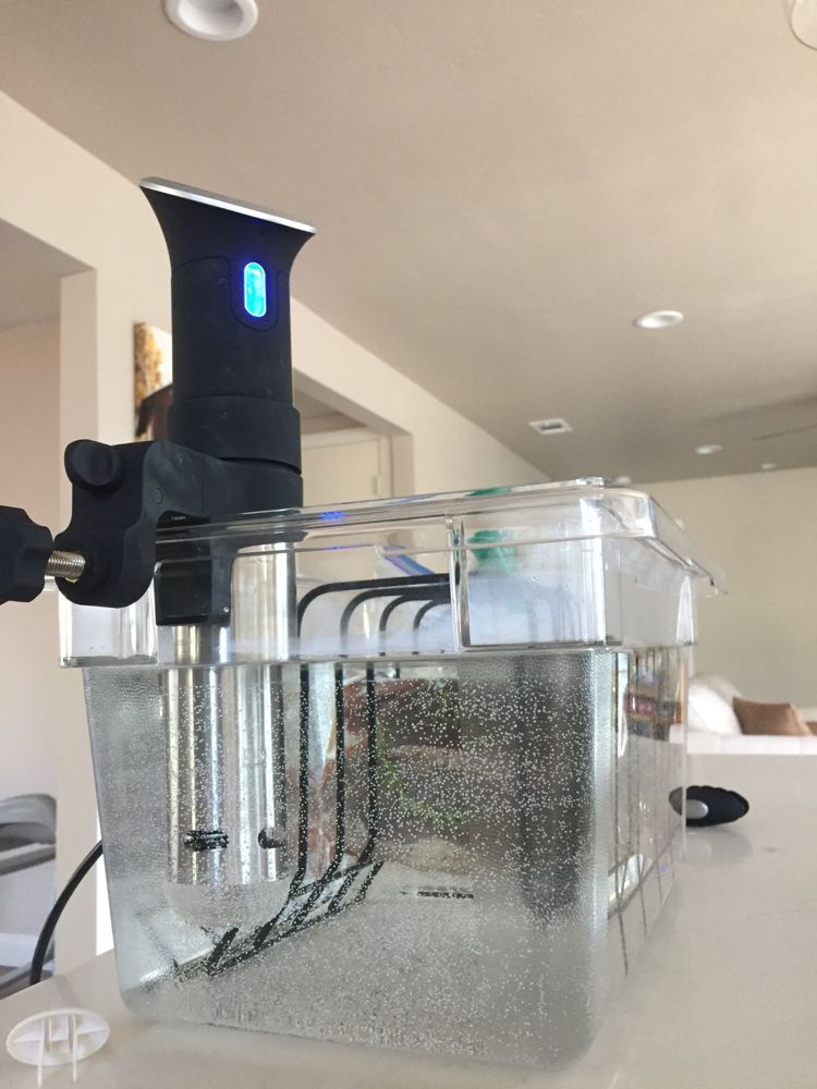 A clear bath container with a clamped circulator and a rack holding bags