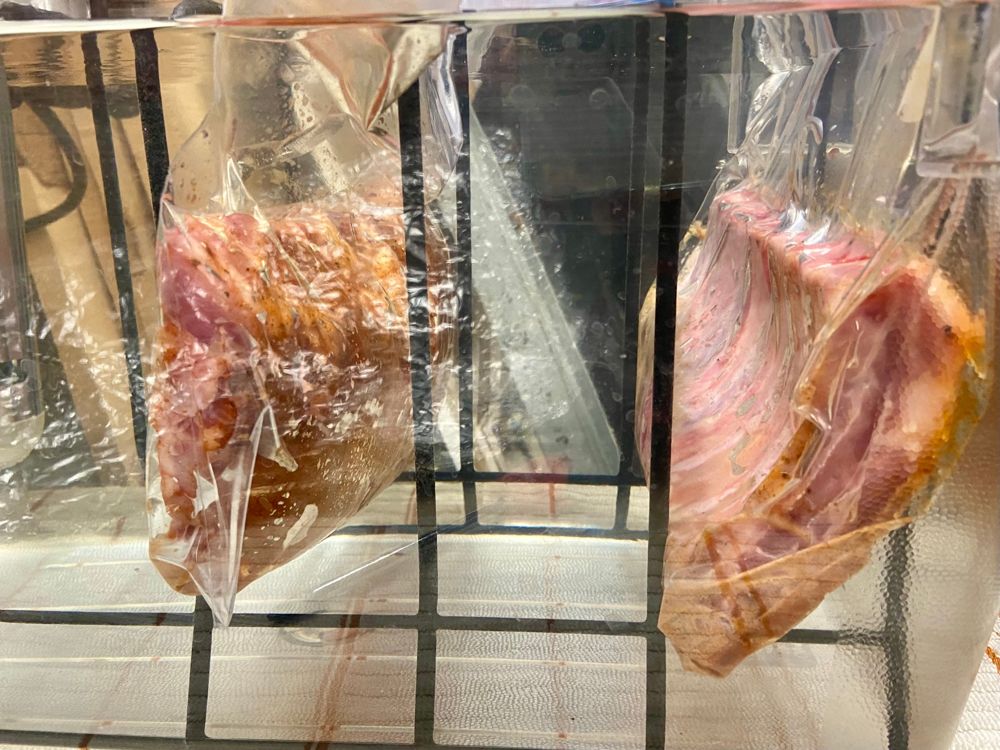 Two bagged seasoned cuts hanging in a water bath